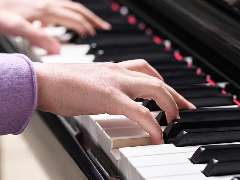 Close-up of a person's hand playing the Yamaha Clavinova CLP-875PE