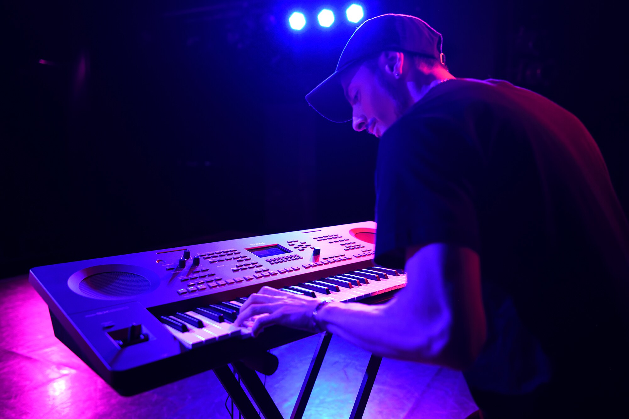 En person som spelar på en Yamaha arranger workstation på ett stativ i scenbelysning
