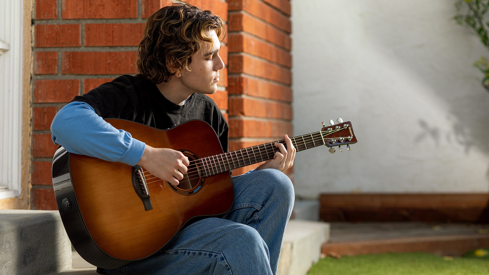 En man som spelar på en akustisk TAG1 E-gitarr utomhus
