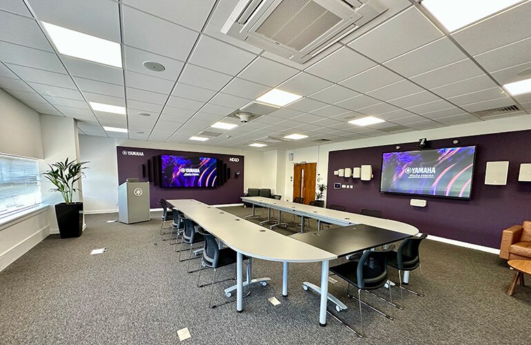 Milton Keynes training facility with tables, chairs, display screen, and audio equipment.