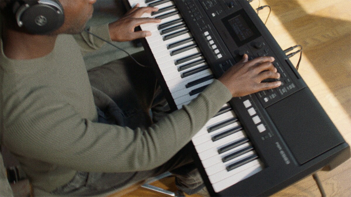 En person som spelar Yamaha Portable Keyboard PSR-E483 med hörlurar