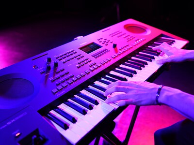 Närbild på händer som spelar på ett keyboard under ett liveframträdande.