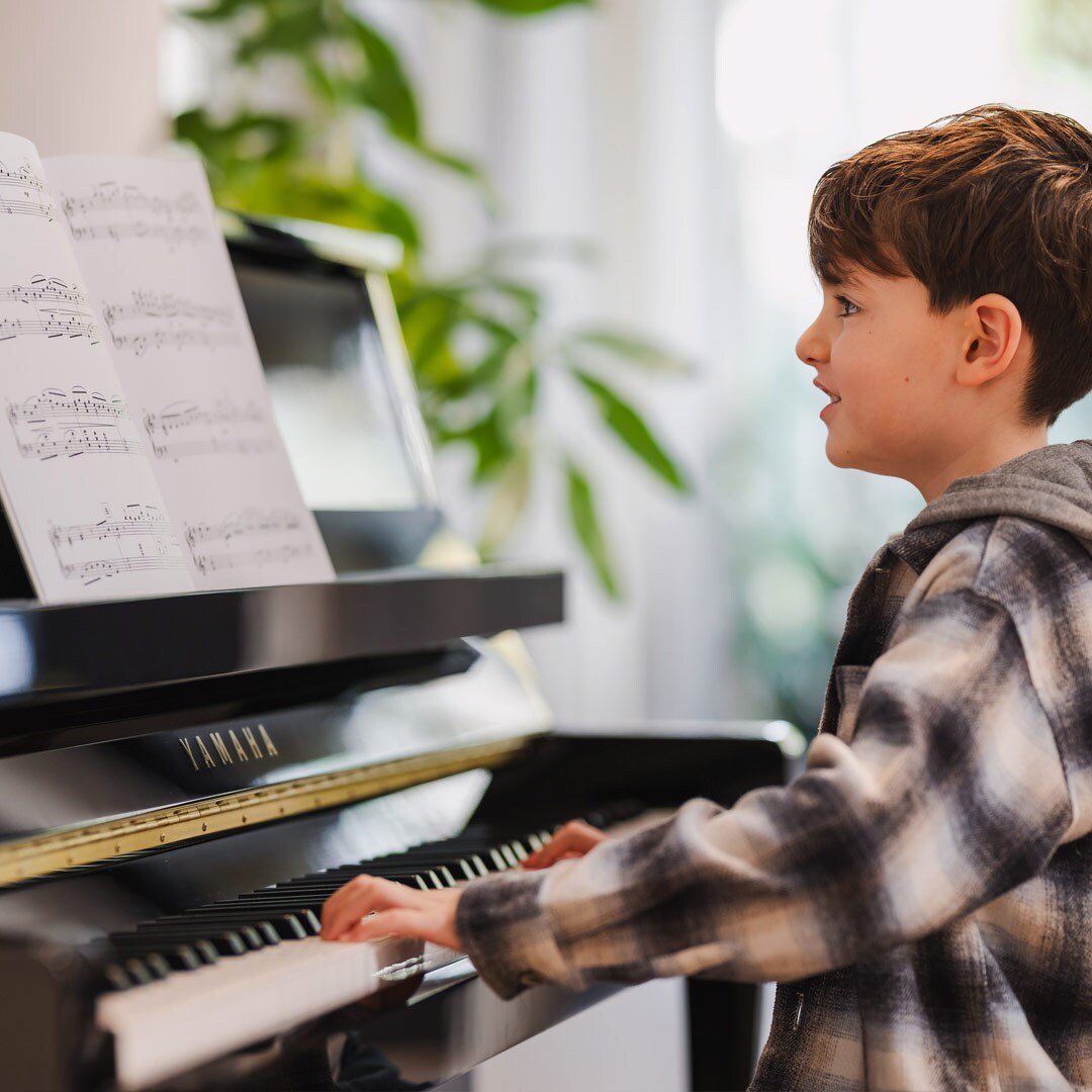 Ett barn som spelar på ett upprättstående piano i B-serien