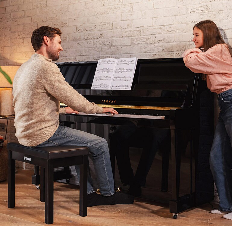 En mamma och dotter som spelar på ett upprättstående piano i B-serien
