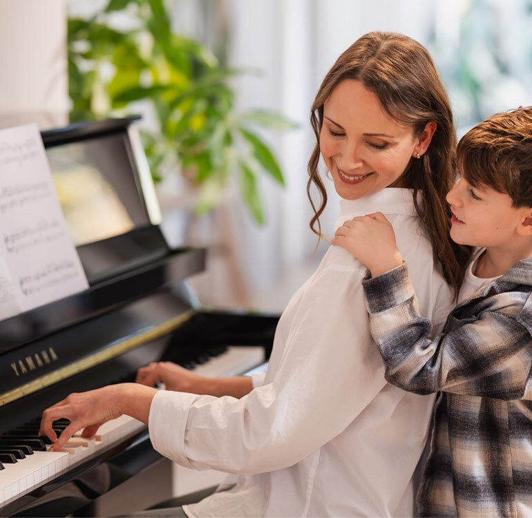 En mamma och dotter som spelar på ett upprättstående piano i B-serien