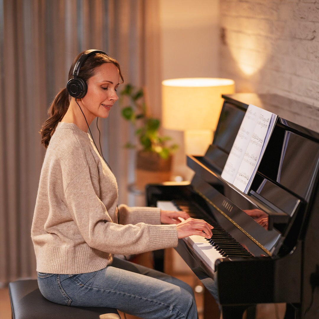 En kvinna som spelar piano med hörlurar