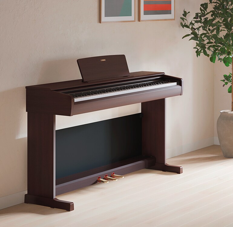 Ett vardagsrum med ett ARIUS-piano, krukväxter och en soffa, harmoniskt integrerat med inredningen