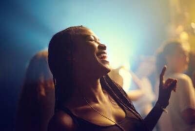 A woman smiling and enjoying music at a live event.